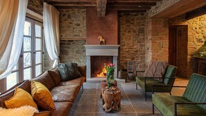 A cozy living room with a stone fireplace, leather sofa, and green armchair. - La Tuscia - Tenuta di Toscana Boutique Villa (Gaiole in Chianti)