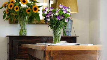 Une table en bois ornée d’un vase contenant des fleurs violettes et blanches, et d’un autre vase avec des tournesols.