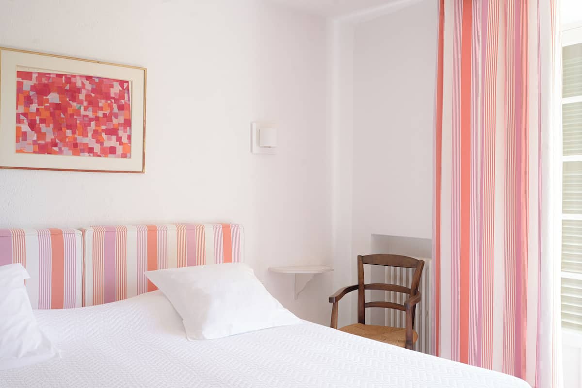 Une chambre à coucher comprenant un lit, une chaise, une petite table et un luminaire fixé au mur.