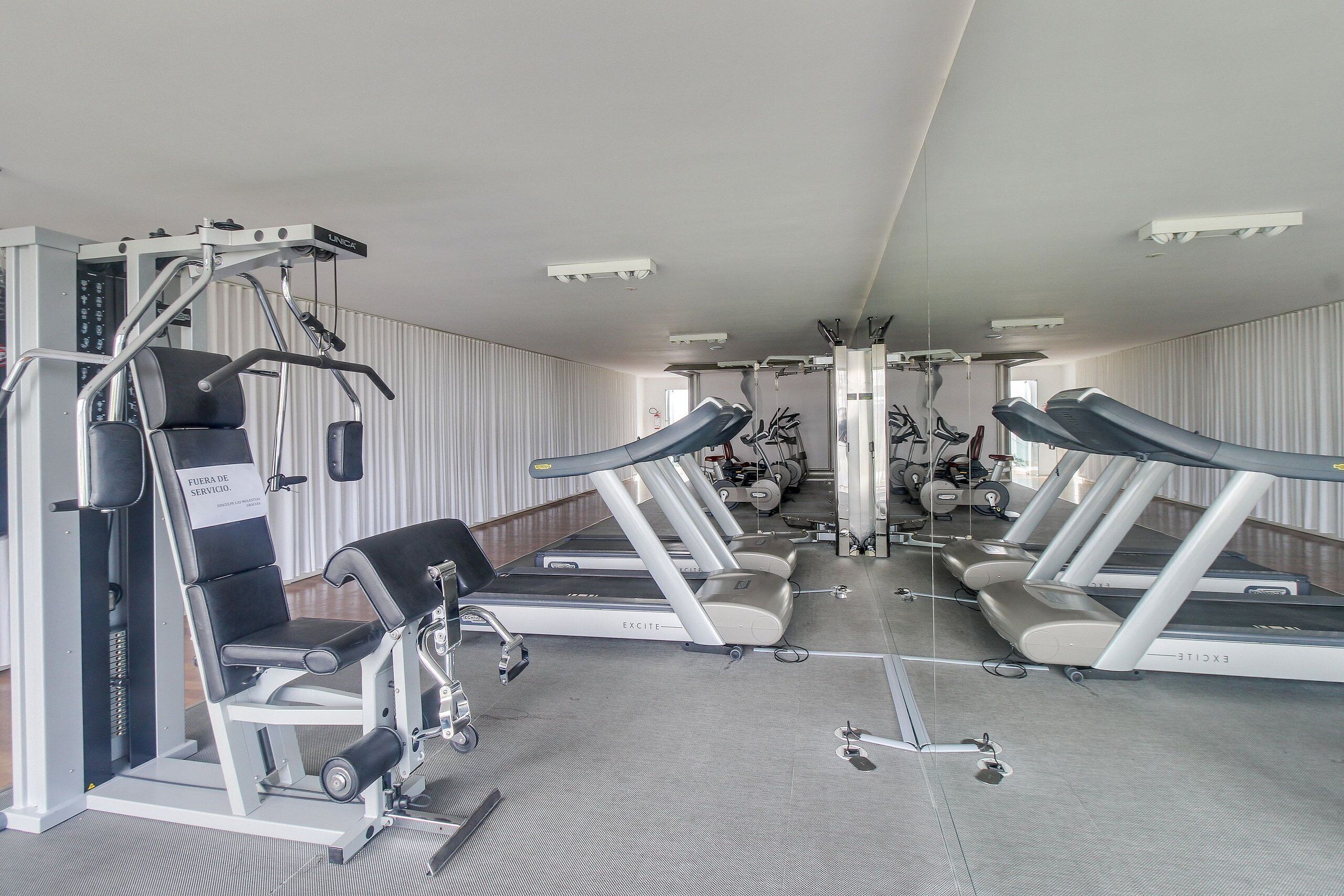 A gym with treadmills, weight machines, and a mirror.