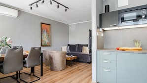 Un espace de vie moderne comprenant un coin repas, un canapé, une cuisine équipée d’un four à micro-ondes et un luminaire au plafond.