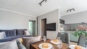 Un salon moderne comprenant un canapé, une table à manger et un coin cuisine.