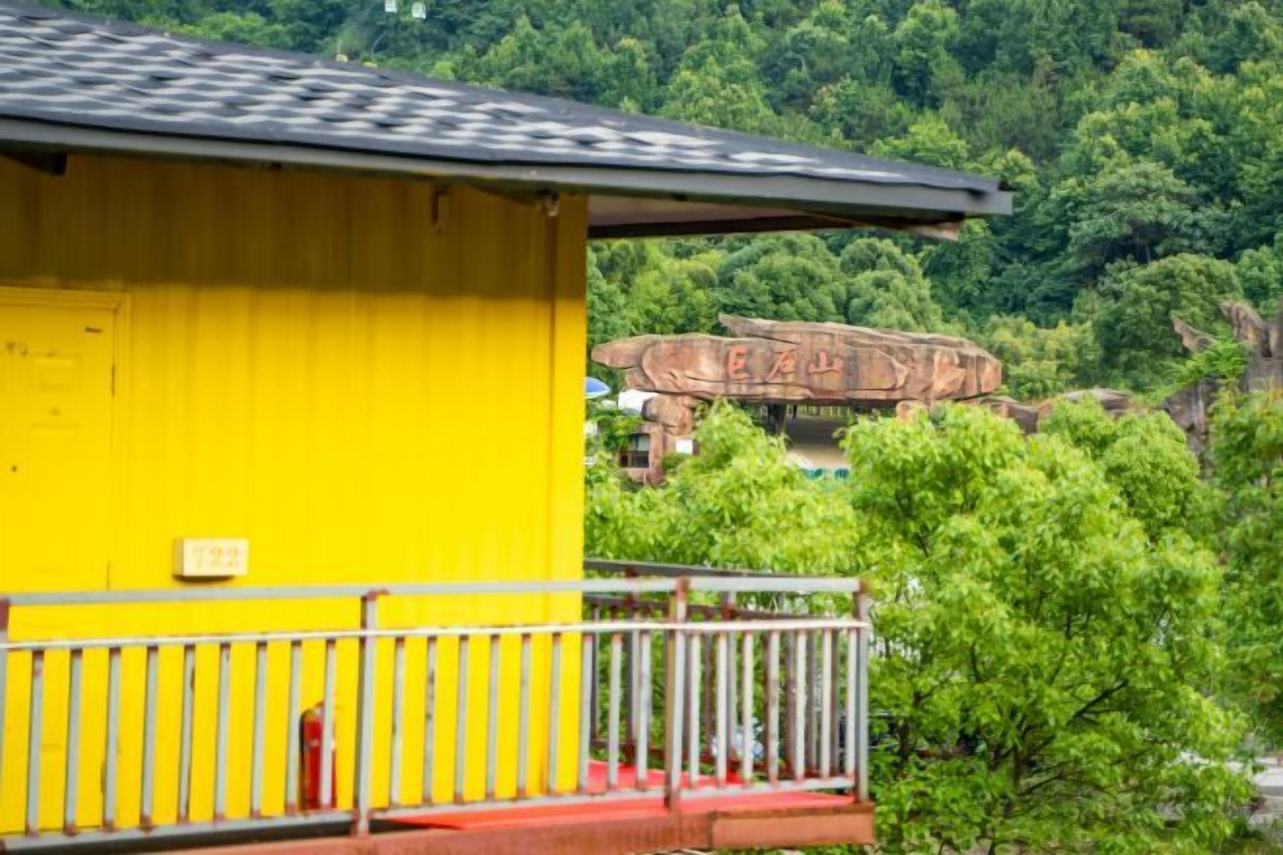 Un edificio amarillo con un balcón, un hidrante rojo y un acantilado rocoso al fondo.