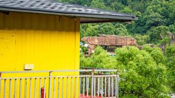 Un edificio amarillo con un balcón, un hidrante rojo y un acantilado rocoso al fondo.