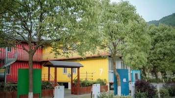 Un edificio colorido con un letrero con el número 7, rodeado de árboles y follaje.