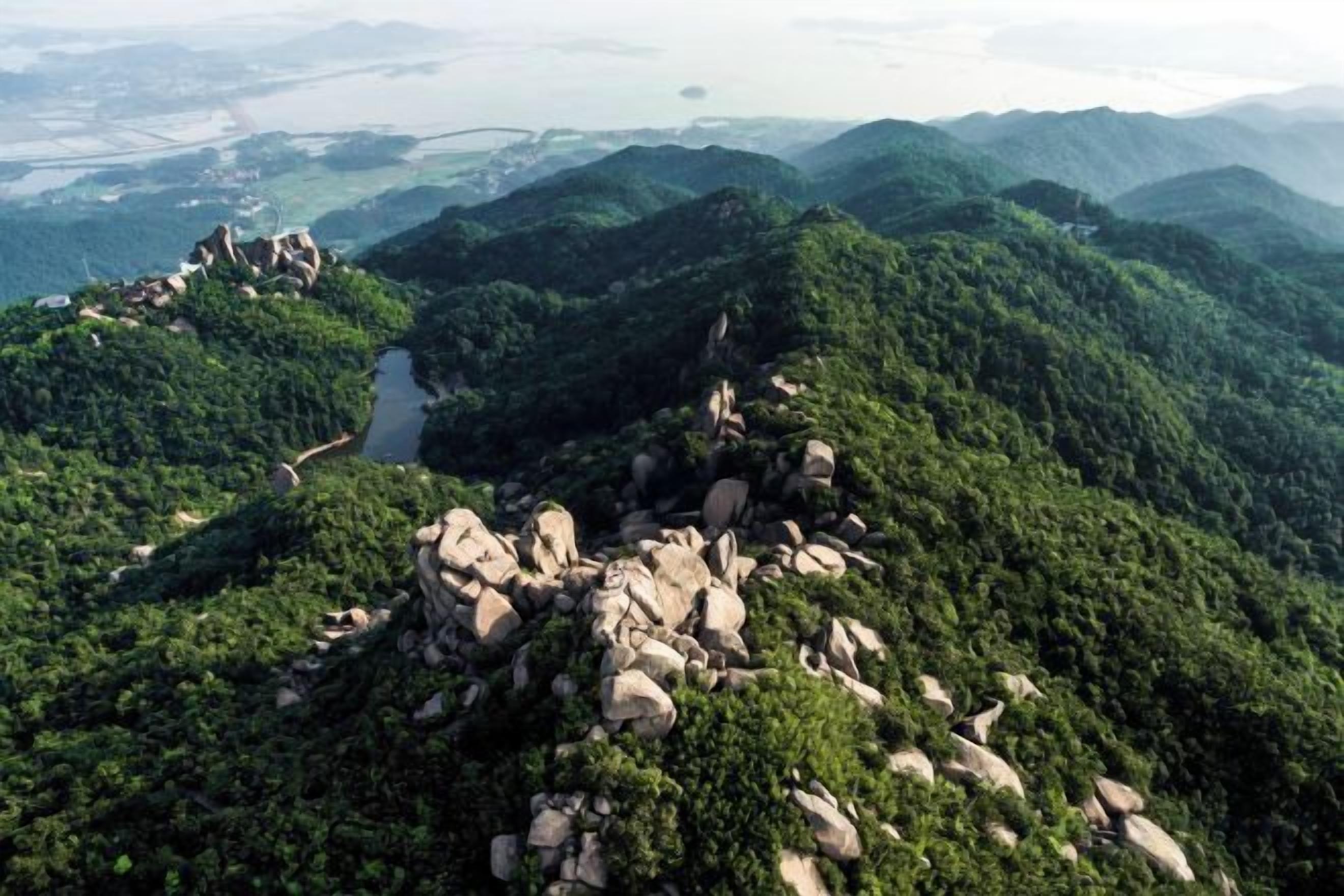 Un paisaje montañoso con un camino serpenteante y afloramientos rocosos.