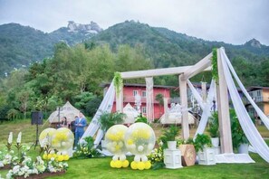 An outdoor wedding setup with a white canopy and floral arrangements.