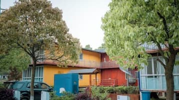 A residential building with a yellow exterior, a blue utility box, and a staircase leading to a balcony.
