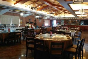 A restaurant with multiple dining tables and chairs, a brick wall, and hanging lights. - Anqing Jushishan LOVE Homestay (Anqing)