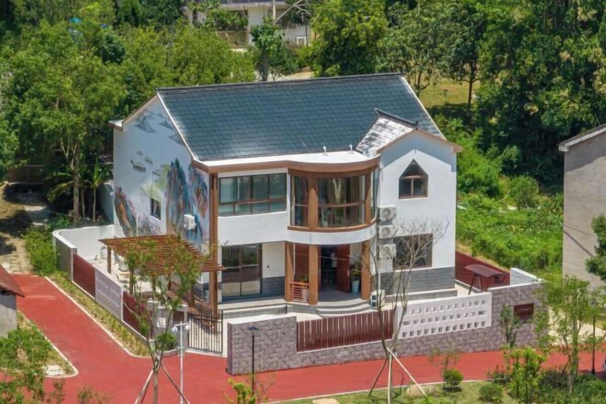 A modern two-story house with a curved balcony, large windows, and a stone facade.