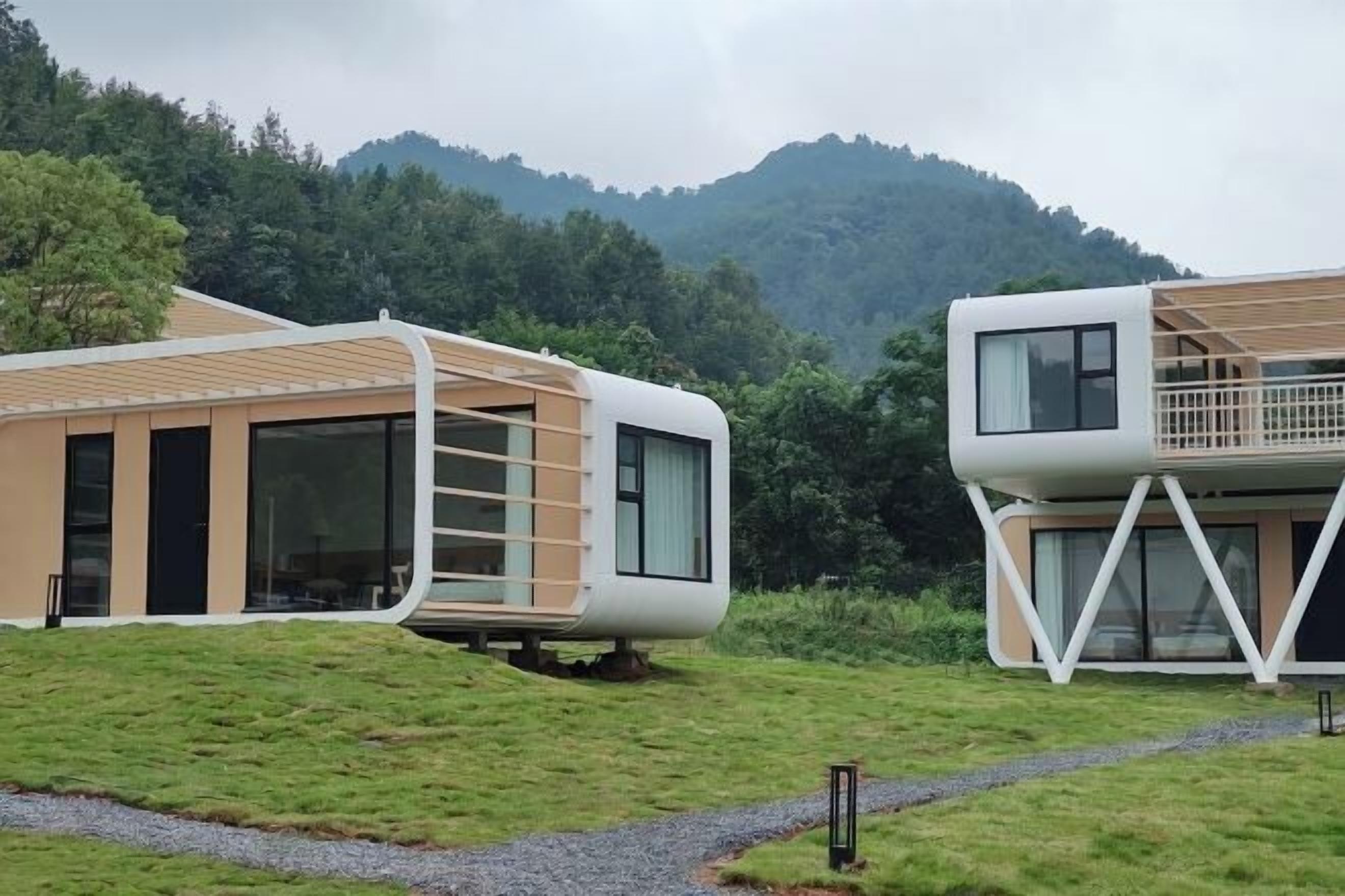 Two modern, curved buildings with large windows, set against a mountainous backdrop.