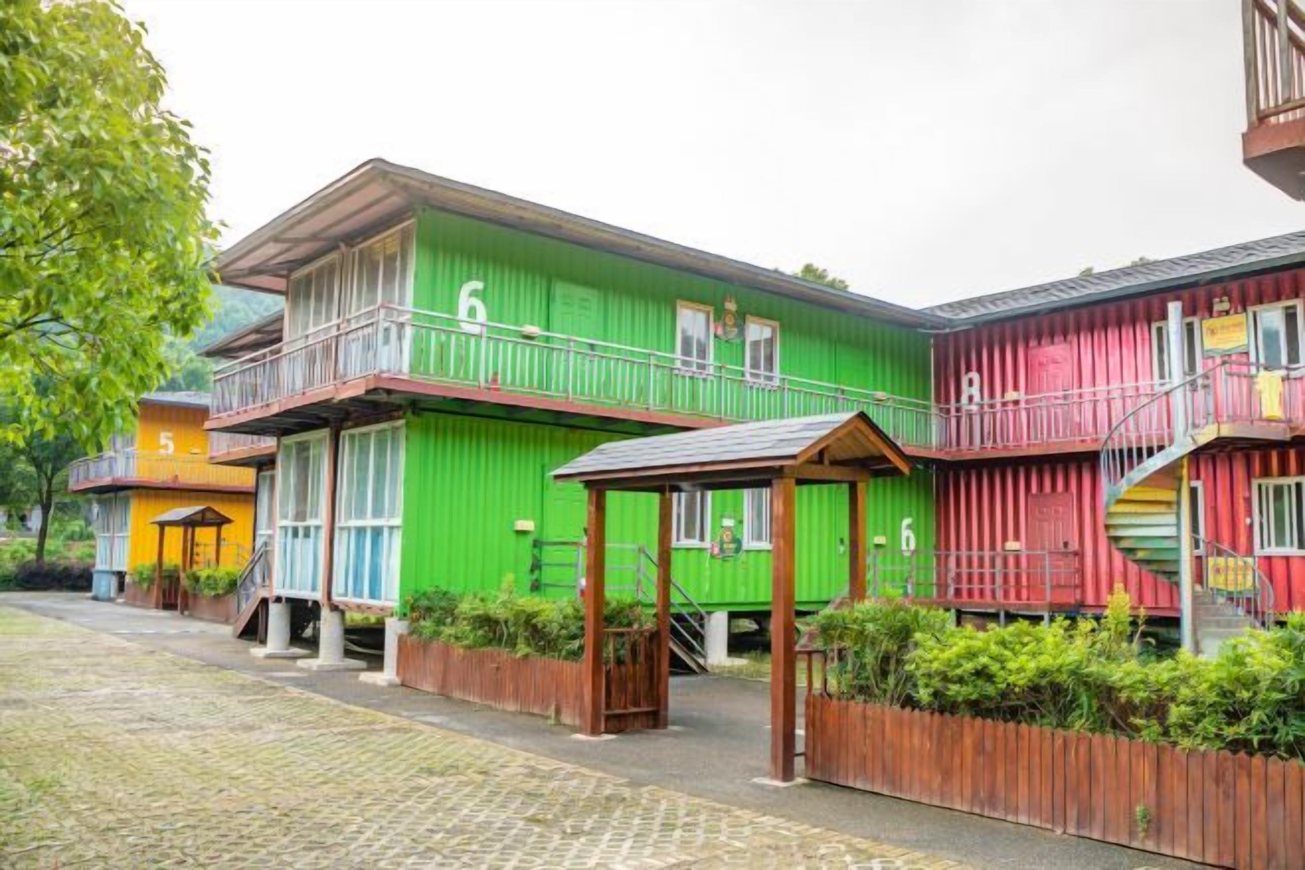 A row of colorful buildings with balconies, wooden fences, and a paved walkway.