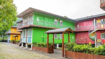 A row of colorful buildings with balconies, wooden fences, and a paved walkway.