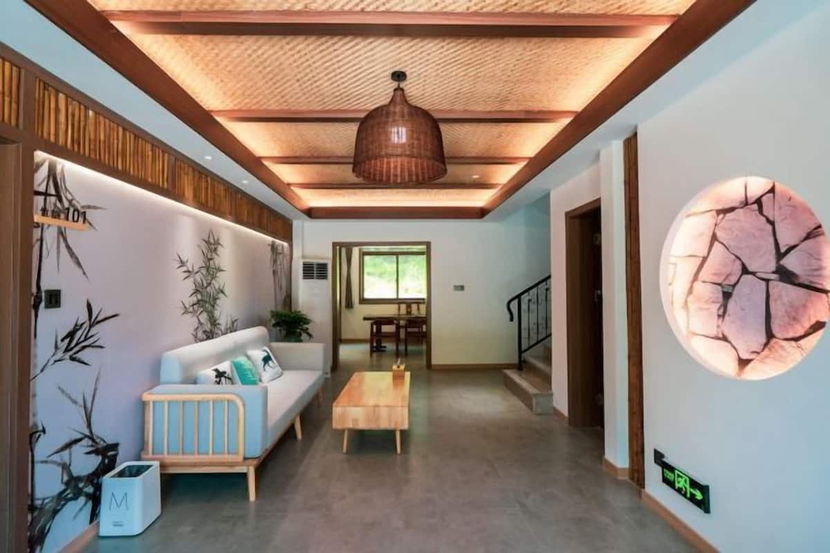 Un intérieur moderne avec un plafond en bois, un canapé, une table basse et un mur orné d’un motif circulaire.