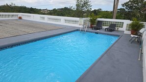 Una piscina rettangolare con acqua cristallina e blu, circondata da un muro bianco con ringhiera per balcone.
