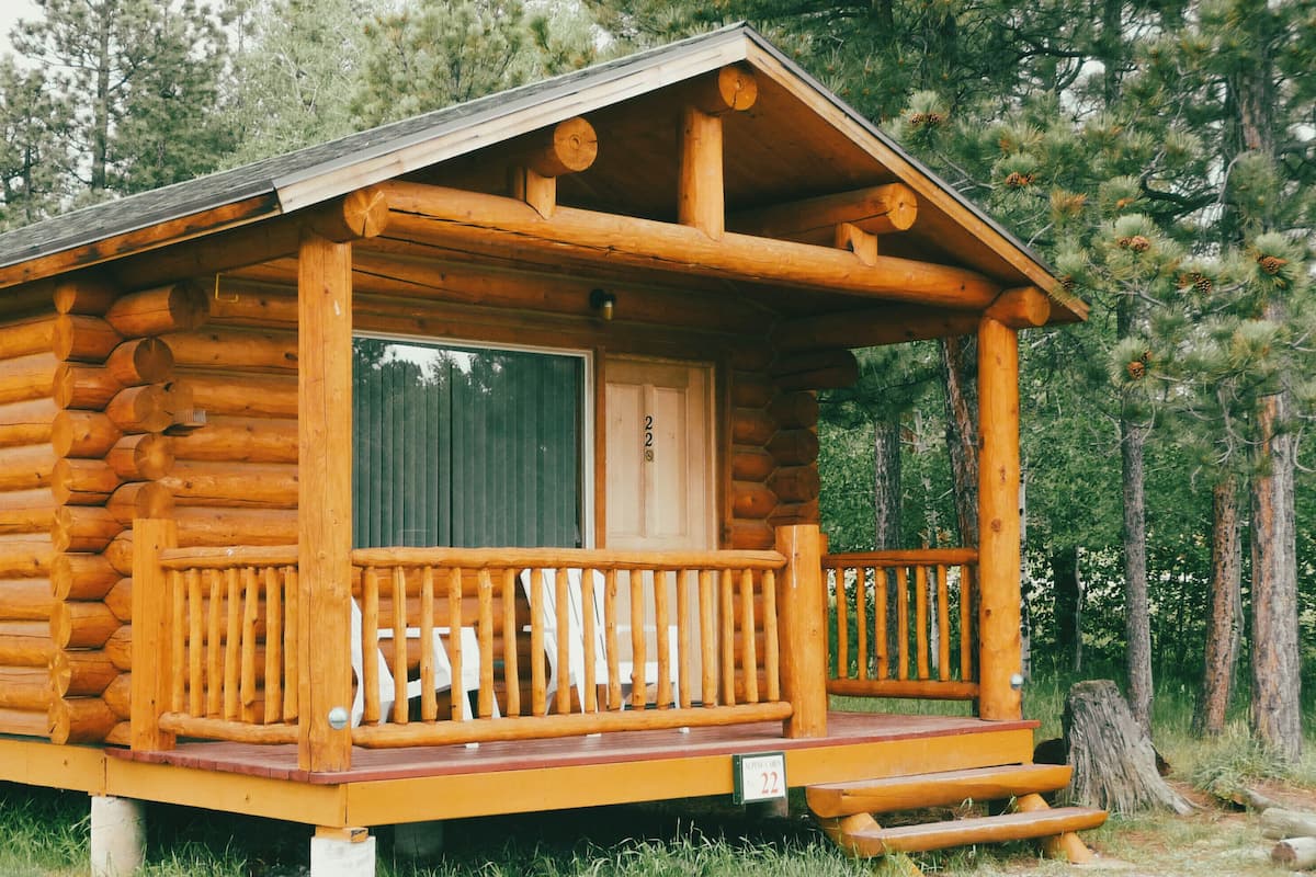 A log cabin with a porch, a window, and a door.