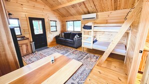 A cozy cabin interior with a wooden floor, a sofa, a dining table, and a bunk bed. - Red Canyon Lodge (Dutch John)