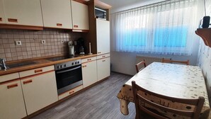 A kitchen with beige cabinets, a wooden countertop, an oven, and a dining table with chairs.