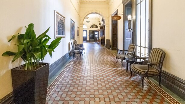 Un couloir avec des carreaux de sol à motifs, des chaises et une plante en pot.