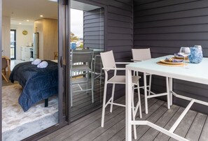 Une chambre moderne avec un lit, une table à manger et des chaises, et une vue à travers une porte vitrée.