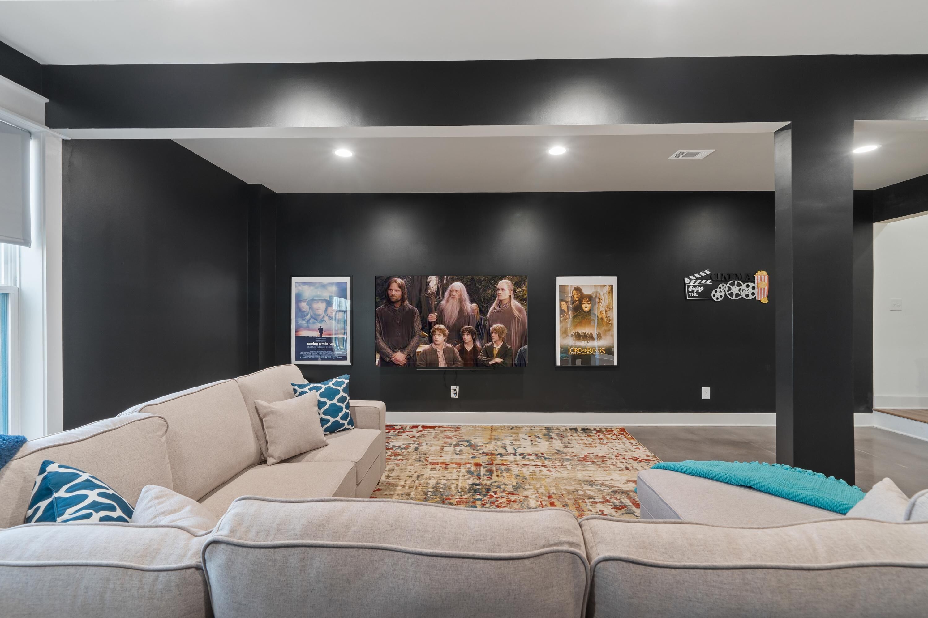 A modern living room with a large sectional sofa, a patterned rug, and artwork on the walls.