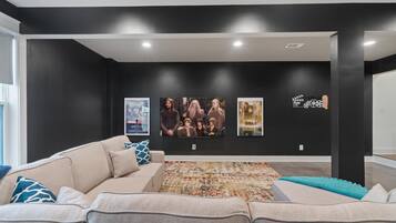 A modern living room with a large sectional sofa, a patterned rug, and artwork on the walls.