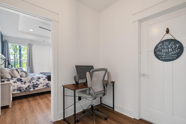 A bedroom with a bed, a desk with a computer, and a door with a sign. - Lakefront Bliss - Fully Loaded (Eatonton)