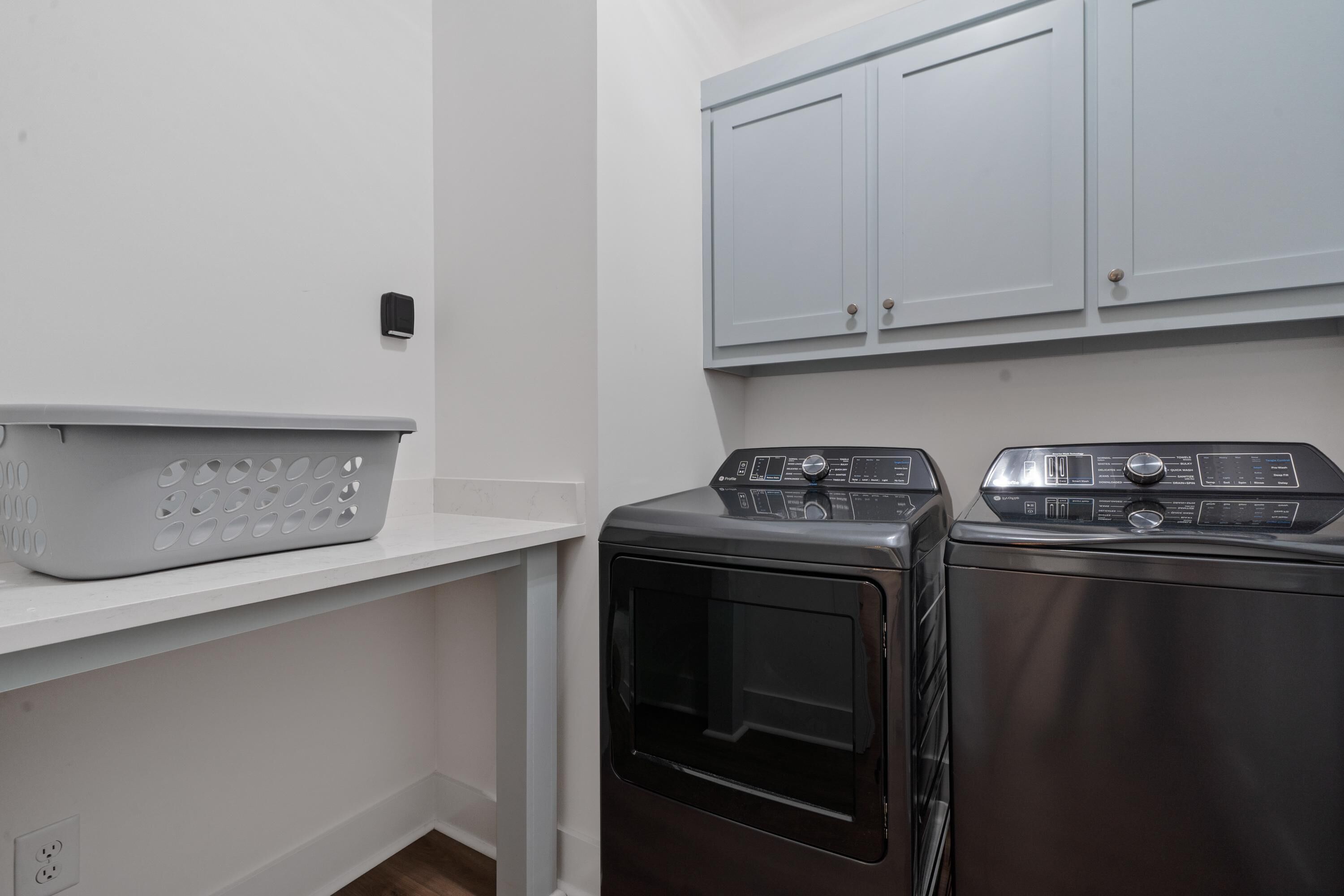 A laundry room with a washing machine, dryer, and a basket on a shelf.
