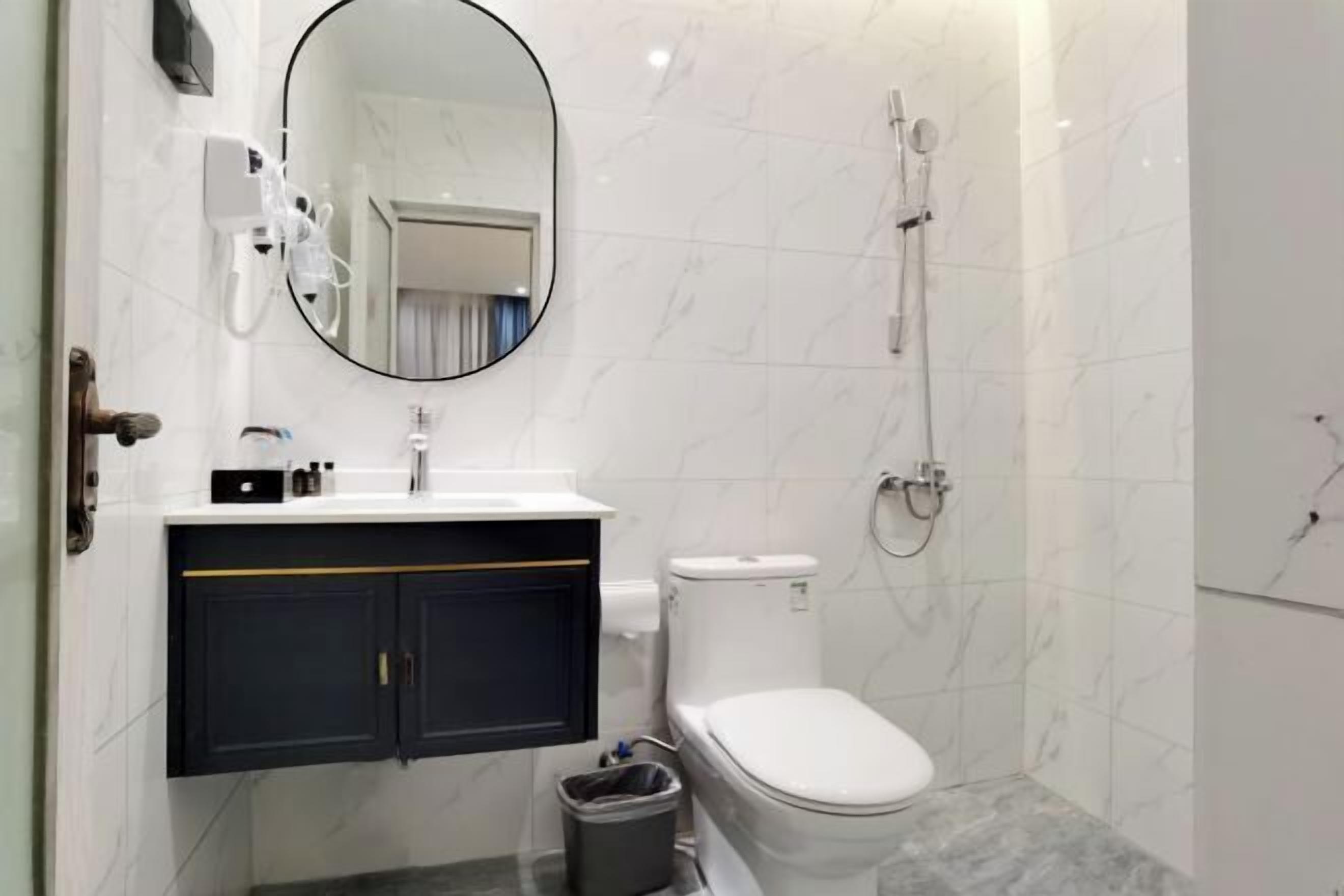 Uma casa de banho moderna com sanita branca, lavatório com espelho acima e zona de duche.