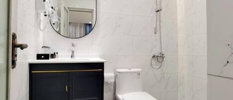 A modern bathroom with a white toilet, a sink with a mirror above it, and a shower area.