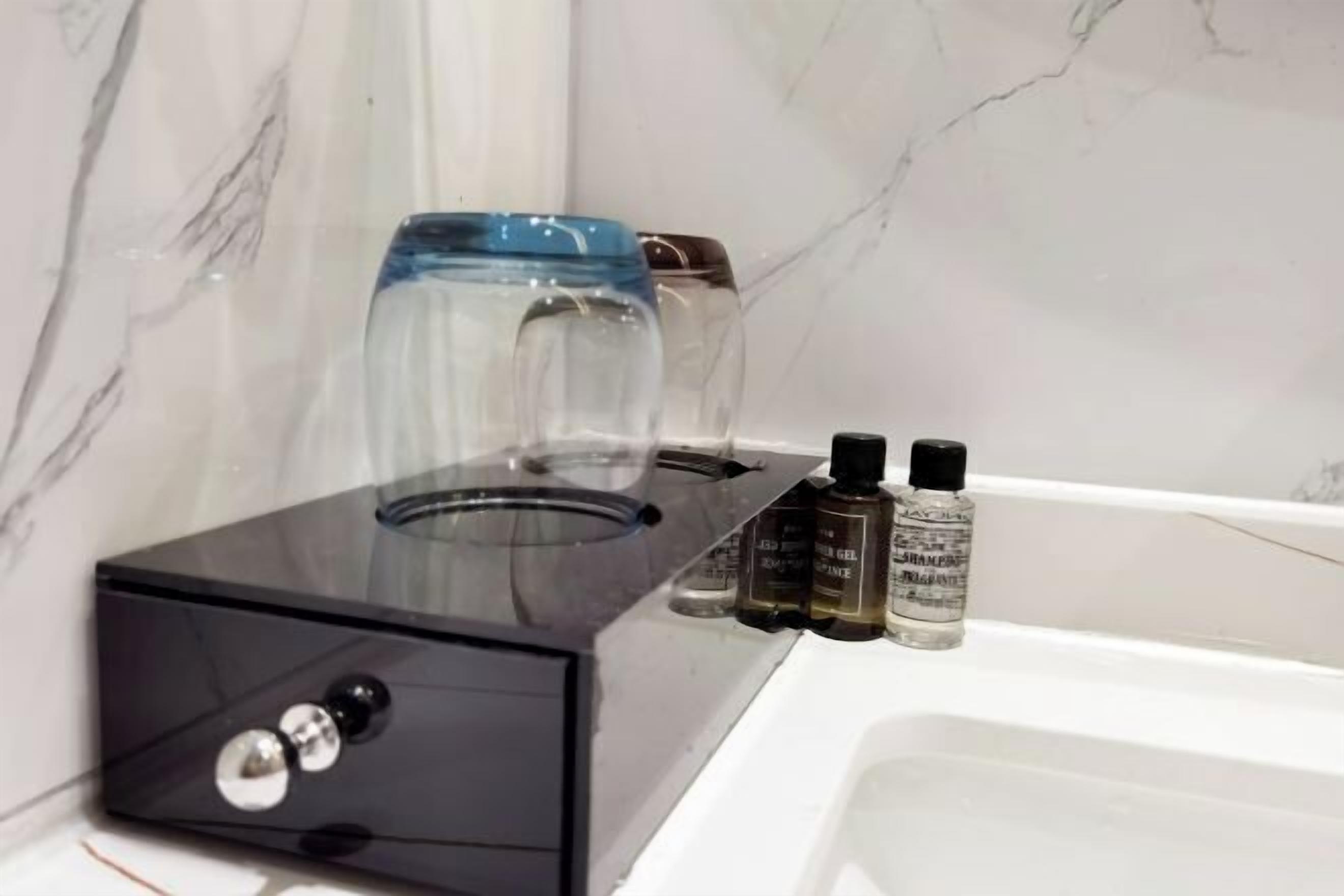 A bathroom with a black countertop, a glass jar, and three bottles of liquid soap.
