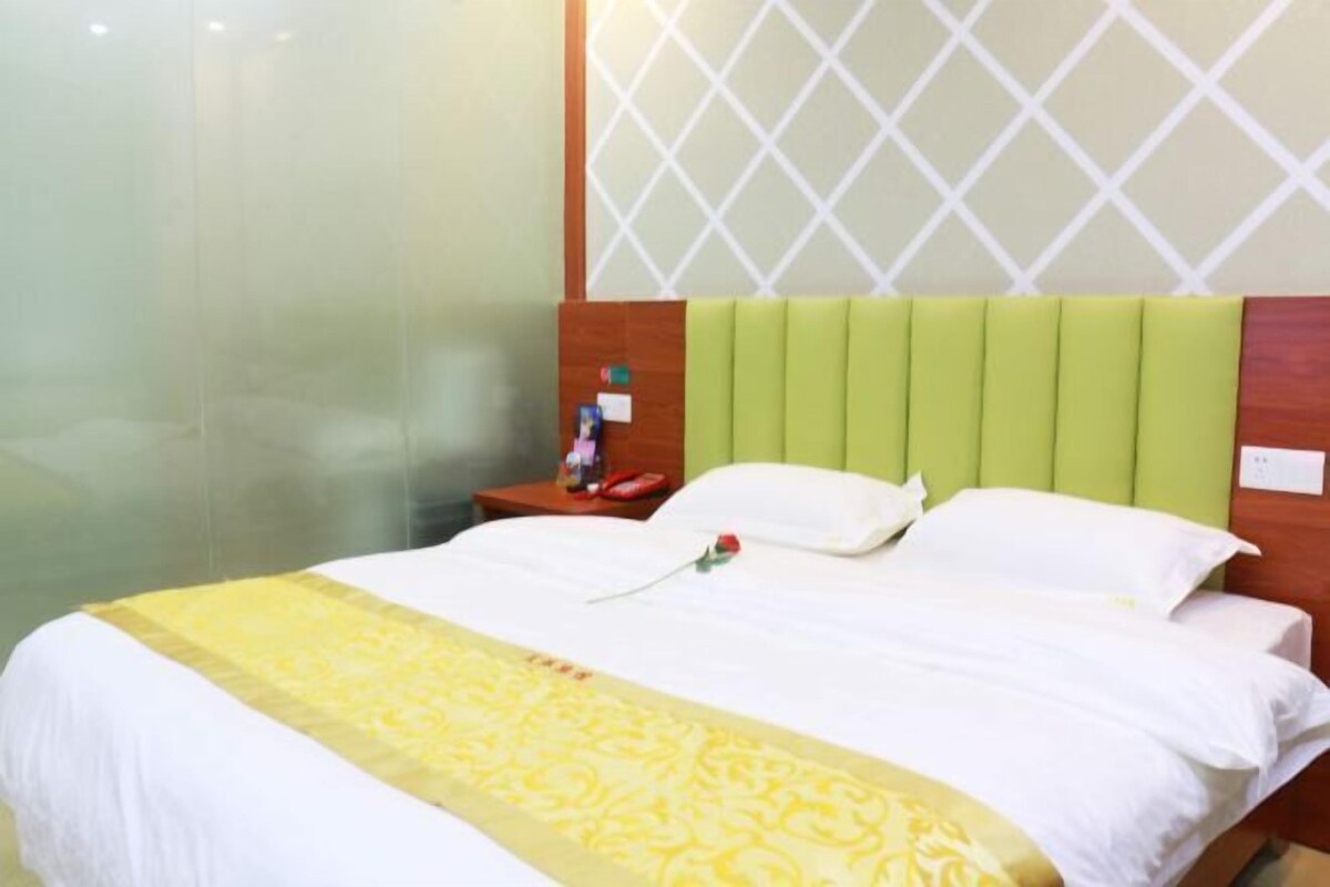 A hotel room with a bed, a nightstand, and a wall-mounted TV.