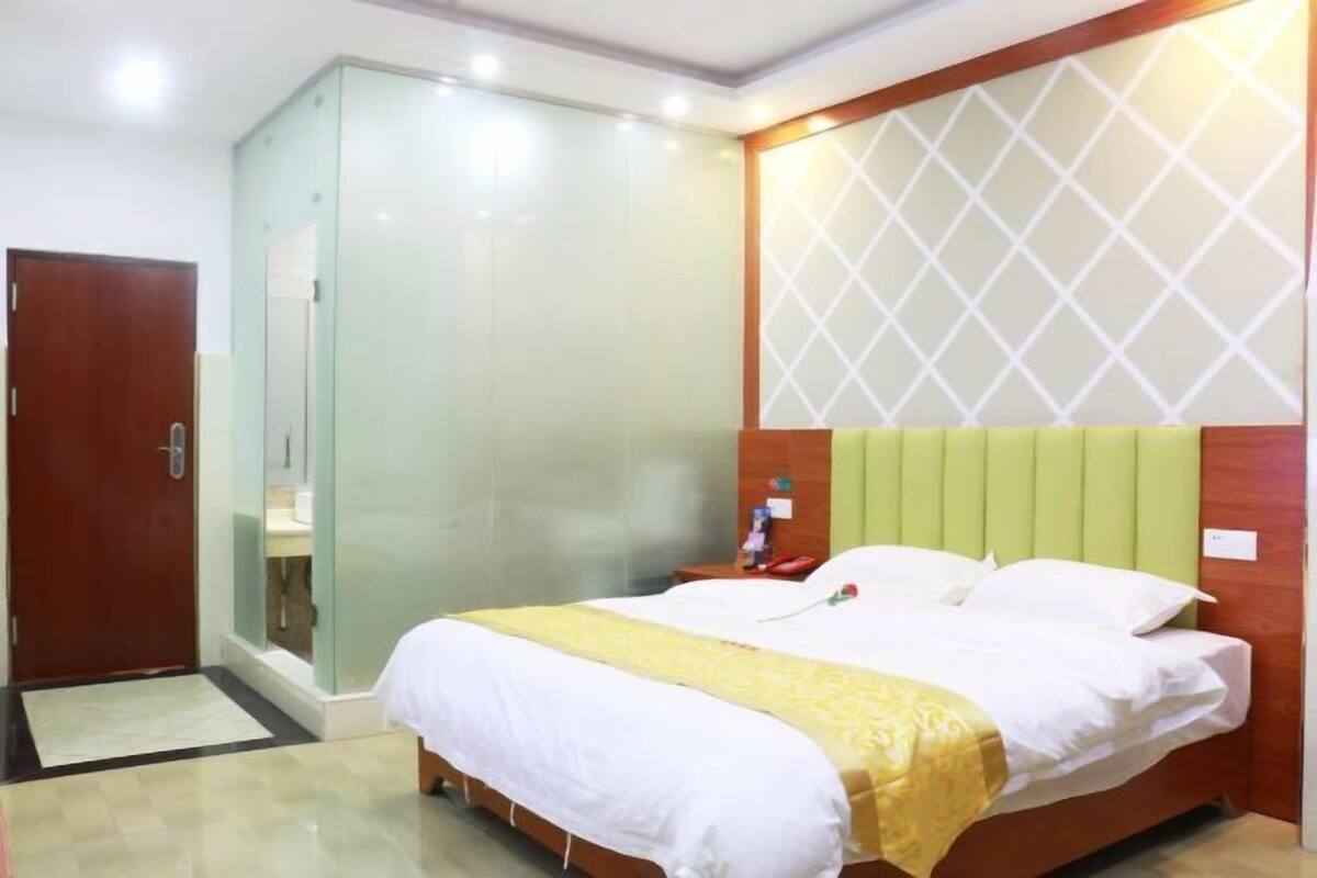 Une chambre d’hôtel avec un lit, une table de chevet, un miroir et une porte.