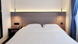 Una habitación de hotel moderna con una cama bien hecha, una mesita de noche con lámpara y un cabecero con iluminación integrada.