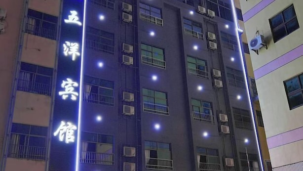 Un edificio de hotel de varios pisos con señalización iluminada y unidades de aire acondicionado.