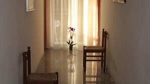 A hallway with two wooden chairs, a potted plant, and a framed picture on the wall. - Hotel Orchidea (Rimini)