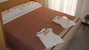 A hotel room with a bed, a nightstand, a lamp, and a window with curtains. - Hotel Orchidea (Rimini)