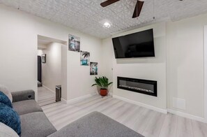 Uma sala de estar moderna com televisão de tela plana, lareira e escada para outro cômodo.