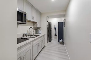 A modern kitchen with white cabinets, a microwave, a stove, and a refrigerator.
