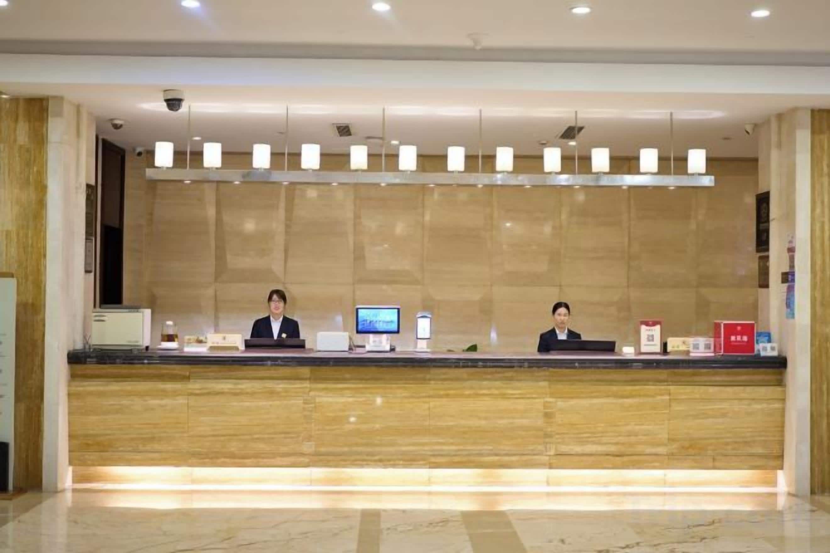 Una reception con due addetti, un monitor a schermo piatto e una macchina da caffè rossa.