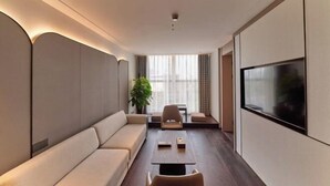 Una sala de estar moderna con sofá, mesa de centro, televisor y planta.