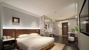 Una habitación de hotel moderna con una cama grande, un revestimiento de mármol, un escritorio y un pequeño rincón de estar.