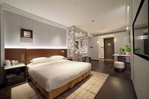 A modern hotel room with a large bed, a marble accent wall, a desk, and a small seating area. - Century Dynasty Hotel (Lanxi)