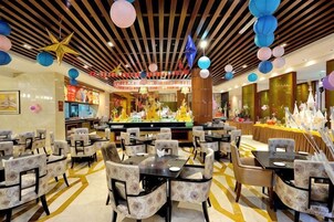 A restaurant with multiple dining tables and chairs, a bar area, and a decorative ceiling with hanging ornaments.