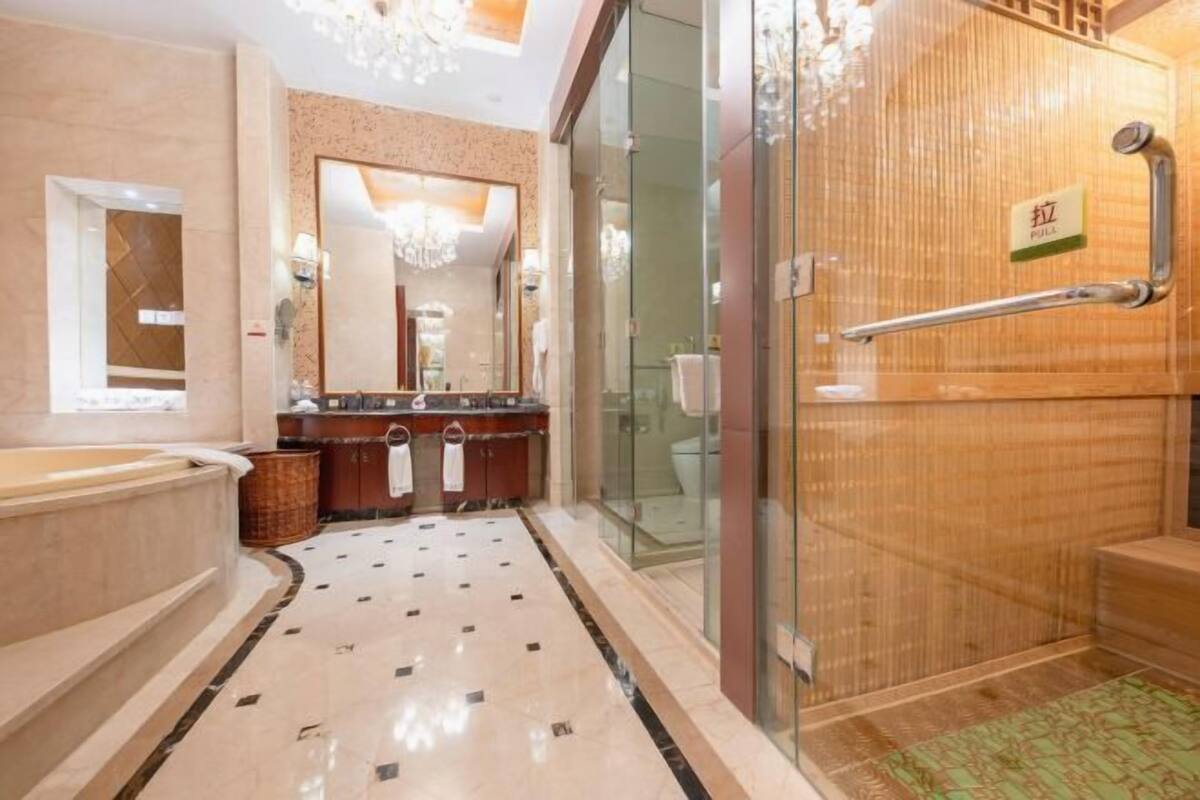 Un baño moderno con un espejo grande, una bañera, un cerramiento de ducha de vidrio y una puerta de madera con picaporte.