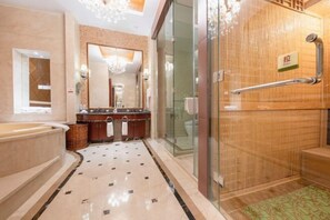 Un baño moderno con un espejo grande, una bañera, un cerramiento de ducha de vidrio y una puerta de madera con picaporte.