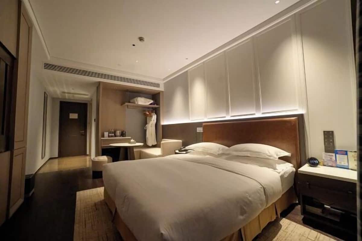 Habitación de hotel con una cama grande, una mesita de noche, un armario y una zona de baño.