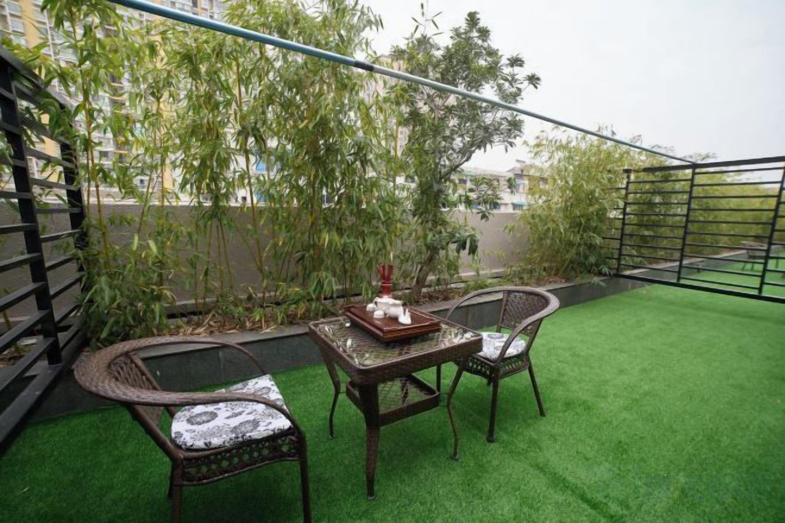 A rooftop terrace with artificial grass, wicker furniture, and a railing.
