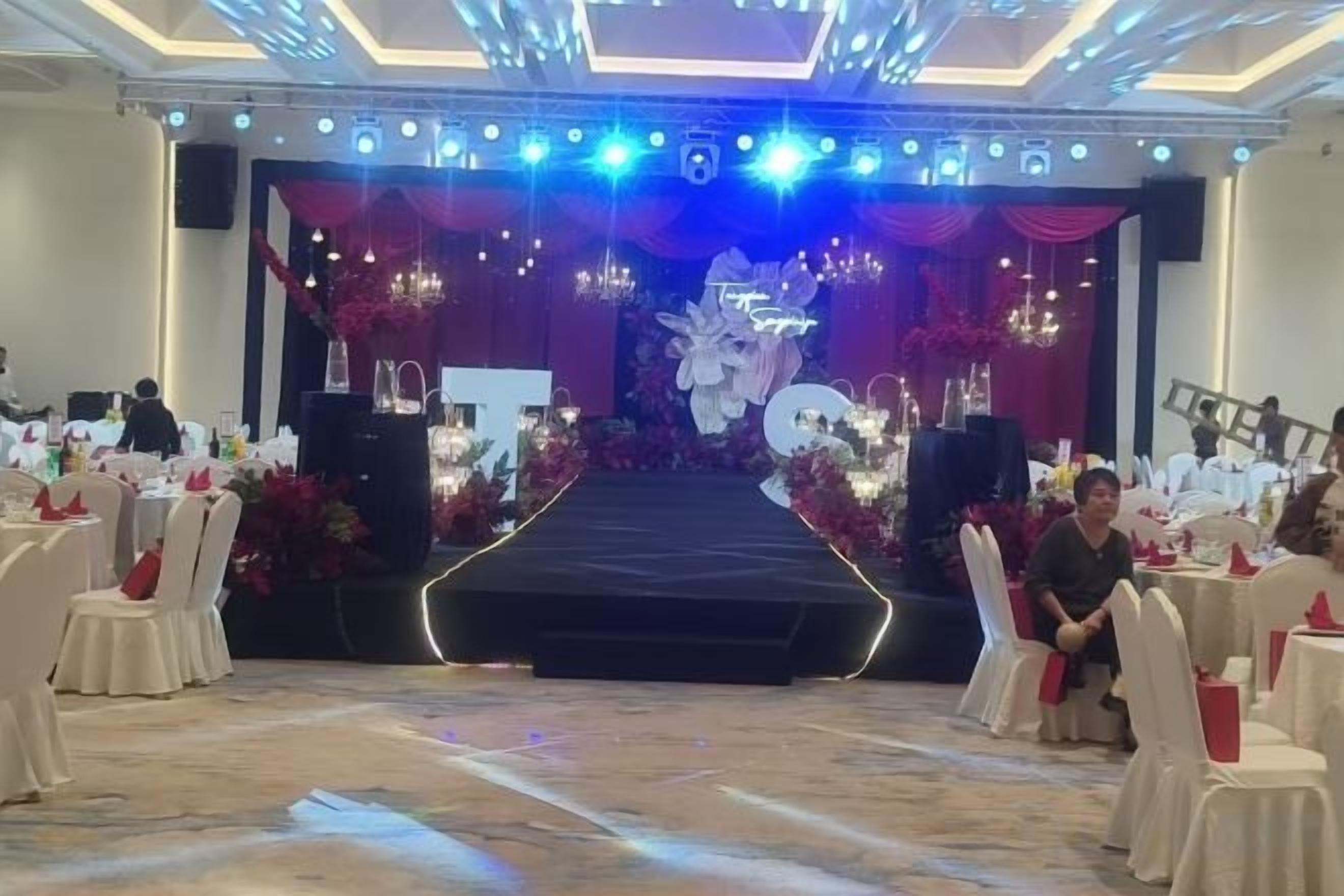 Una sala da banchetto con un palco, tavoli e sedie disposti per un evento.