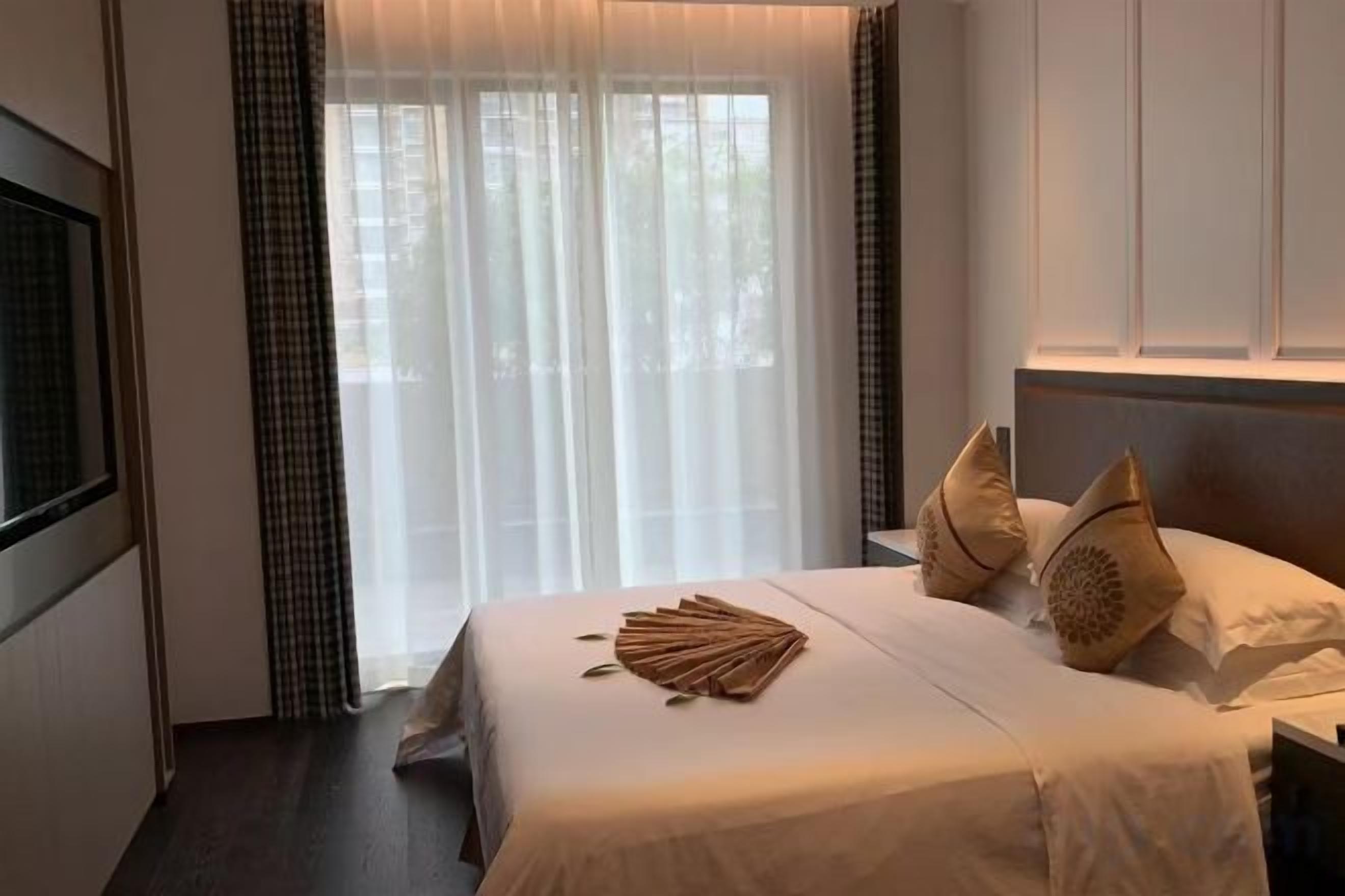 Una habitación de hotel con cama, cortinas y cabecero.